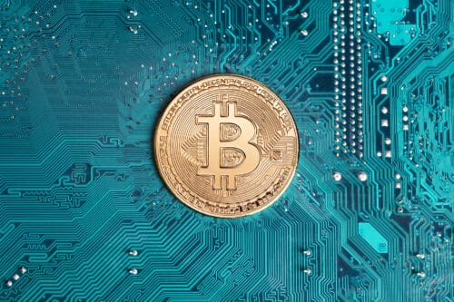 Jasien, Poland, 18 February 2021: Golden bitcoin replica on computer circuit board. This file is cleaned and retouched.